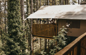 Vista de una tienda safari con balcón y servicios sanitarios en Camping Luna del Monte, Italia.