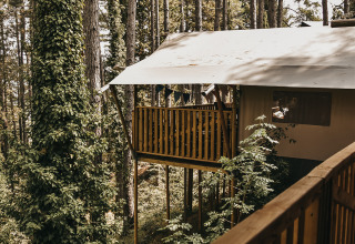 Vista su tenda safari con balcone e servizi igienici al Camping Luna del Monte, Italia.