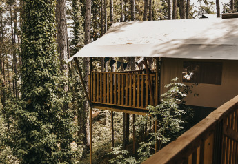Vista de una tienda safari con balcón y servicios sanitarios en Camping Luna del Monte, Italia.