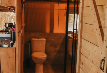 Badkamer met toilet en douche in een safaritent met sanitaire voorzieningen op Camping Luna del Monte, Italië.