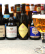 Varias botellas de cerveza y una copa llena en la mesa de un parque vacacional con alojamiento glamping.