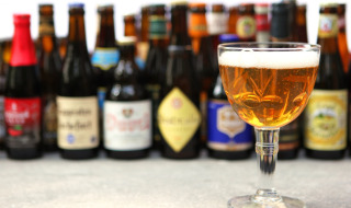 Varias botellas de cerveza y una copa llena en la mesa de un parque vacacional con alojamiento glamping.