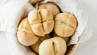 Una cesta de panecillos recién horneados sobre un paño blanco, lista para servir en el desayuno o brunch.