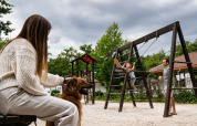 Famiglia al Camping Etxarri, Navarra, Spagna: bambino sull'altalena, donna con cane, cielo nuvoloso.
