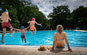 Familie nyder en sommerdag ved poolen i Camping Etxarri, Navarra, Spanien. Børn hopper i vandet.