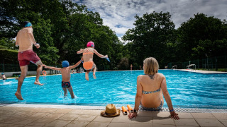 Gezin geniet van een zomerdag bij het zwembad op Camping Etxarri, Navarra, Spanje. Kinderen springen in het water.