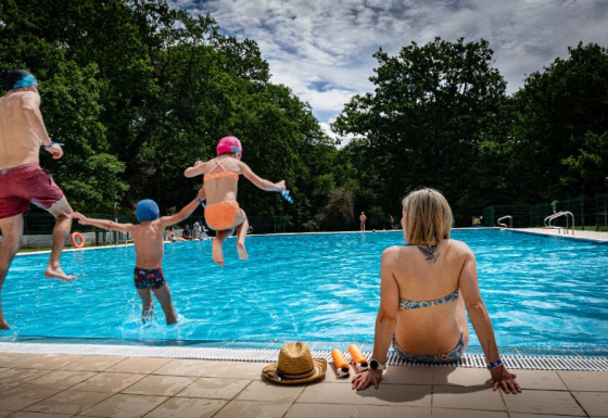 Familie nyder en sommerdag ved poolen i Camping Etxarri, Navarra, Spanien. Børn hopper i vandet.