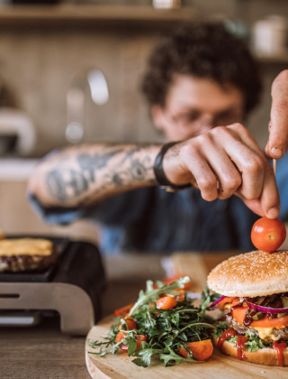 Un chef en ETXARRI-ARANATZ, Navarra, España, decora una hamburguesa con tomate cherry y ensalada fresca.