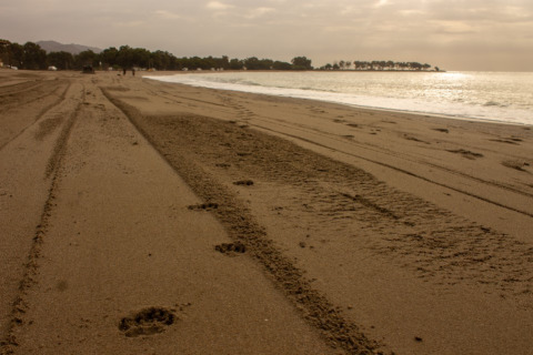 Huellas en la arena al atardecer en la playa del parque vacacional TAIGA Almeria Playa en Andalucía, España.