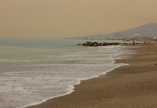 Misty beach scene with gentle waves at Cuevas del Almanzora, Andalusia, Spain, under a hazy sky.