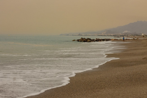 Playa cerca de Cuevas del Almanzora, Andalucía, España, con olas suaves y cielo nublado al atardecer.