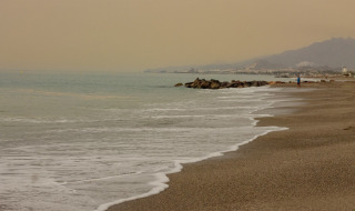 Playa cerca de Cuevas del Almanzora, Andalucía, España, con olas suaves y cielo nublado al atardecer.