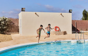 Due ragazzi saltano felici in una piscina al TAIGA Almeria Playa, villaggio turistico in Andalusia, Spagna.