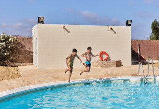 Two boys joyfully jump into a swimming pool at TAIGA Almeria Playa holiday park in Andalusia, Spain.