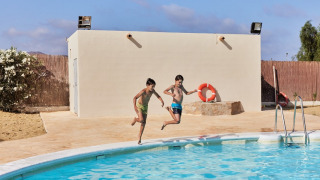 Dos niños saltan felices a la piscina en el parque vacacional TAIGA Almeria Playa en Andalucía, España.