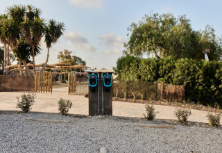 Two electric car charging stations at TAIGA Almeria Playa holiday park in Andalusia, Spain, surrounded by trees.
