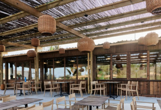 Udendørs terrasseområde på TAIGA Almeria Playa feriepark i Andalusien med træmøbler og hængende lamper.