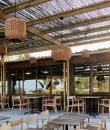 Terraza exterior en el parque vacacional TAIGA Almeria Playa en Andalucía con muebles de madera y lámparas.