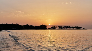 Atardecer sobre el mar en TAIGA Almeria Playa, parque vacacional en Andalucía, España, con árboles en la costa.