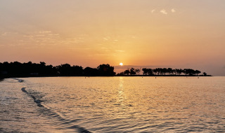 Atardecer sobre el mar en TAIGA Almeria Playa, parque vacacional en Andalucía, España, con árboles en la costa.