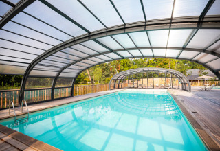 Piscina coperta con tetto trasparente e terrazza in legno a Huttopia Vallée de la Semois, Namur, Belgio.