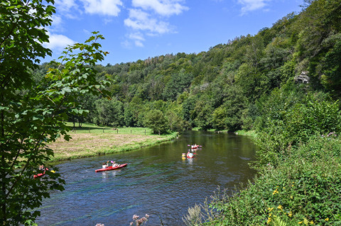 Des kayakistes pagaient sur une rivière entourée de collines verdoyantes à Huttopia Vallée de la Semois, Namur.