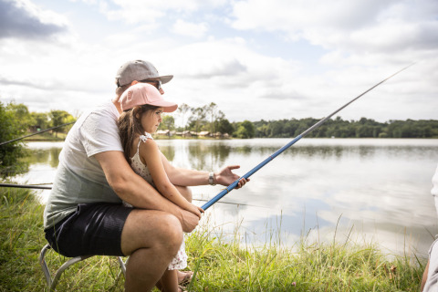 Padre e hija pescando juntos en la orilla del lago en Huttopia Vallée de la Semois, Namur, Bélgica.