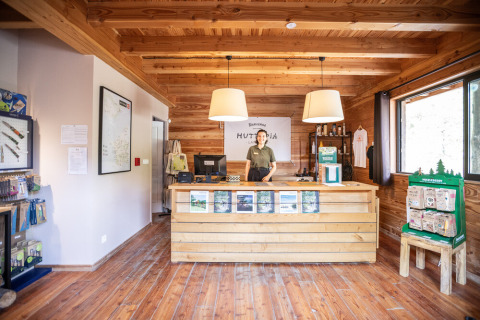 Reception area at Huttopia Vallée de la Semois in Namur, Belgium, with wood decor and a staff member smiling.
