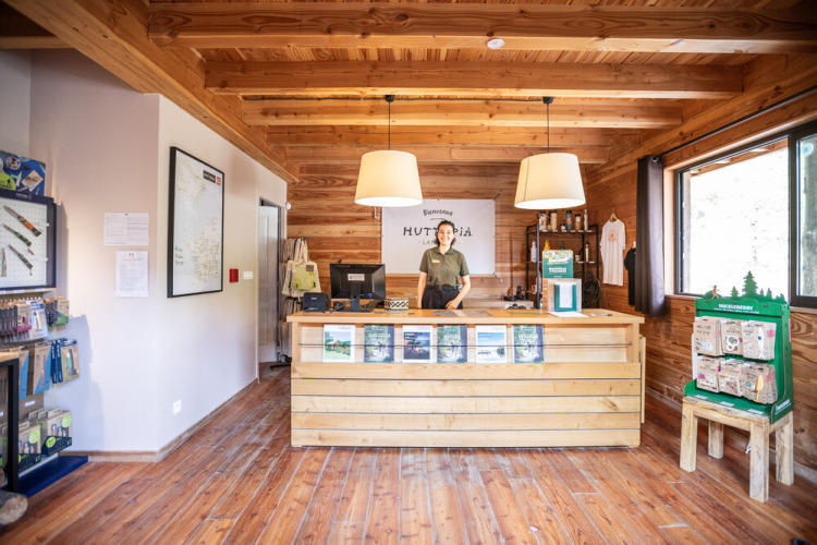 Reception area at Huttopia Vallée de la Semois in Namur, Belgium, with wood decor and a staff member smiling.