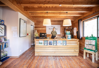 Reception area at Huttopia Vallée de la Semois in Namur, Belgium, with wood decor and a staff member smiling.