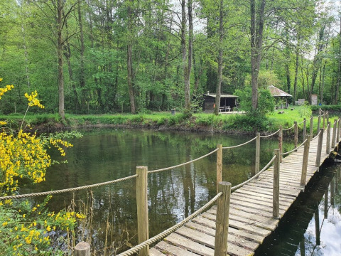 Puente de madera sobre río en Huttopia Vallée de la Semois, parque vacacional en Namur, Bélgica.