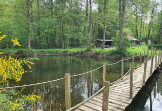 Houten brug over water in Huttopia Vallée de la Semois, vakantiepark in Namur, België.