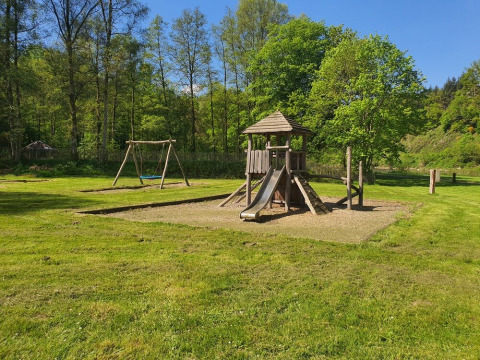 Parque infantil con tobogán y columpios en una zona verde en Huttopia Vallée de la Semois, Namur, Bélgica.