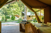View from inside a safari tent at Camping La Colline in Belgium, with wooden furniture and lush greenery outside.