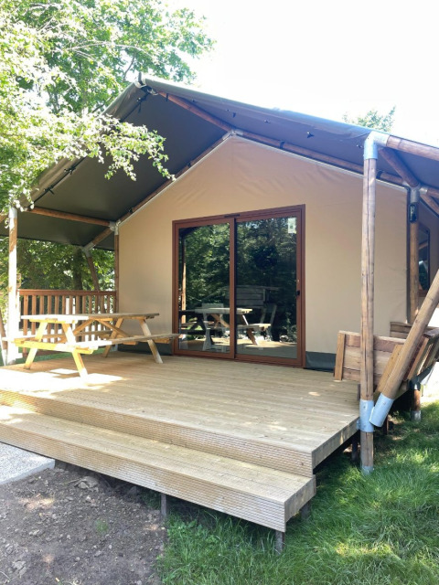 Cabaña de madera con terraza cubierta y mesa de picnic en Urban-Gardens Ieper, parque vacacional de Flandes Occidental, Bélgica.
