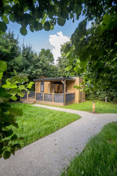 Een moderne houten chalet met overdekt terras in het groen bij Urban-Gardens Ieper, West-Vlaanderen, België.