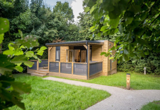 Cabaña moderna de madera con porche cubierto, rodeada de vegetación en Urban-Gardens Ieper, Flandes Occidental, Bélgica.