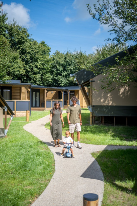 Familia paseando con un niño pequeño por Urban-Gardens Ieper, parque de vacaciones en Flandes Occidental, Bélgica.