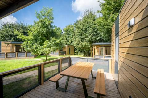 Chalets modernes en bois avec terrasse et bancs à Urban-Gardens Ieper, parc de vacances en Flandre occidentale, Belgique.