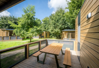 Chalets modernes en bois avec terrasse et bancs à Urban-Gardens Ieper, parc de vacances en Flandre occidentale, Belgique.