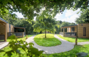 Moderne Holzhütten im Urban-Gardens Ieper Ferienpark in Westflandern, Belgien, mit grünen Wegen.