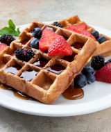 Gofres crujientes con frutas frescas y sirope, servidos en plato blanco en Urban-Gardens Ieper.