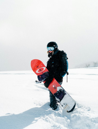 Un snowboarder con casco y mochila se detiene en la nieve profunda cerca de Font Romeu, Occitania, Francia.