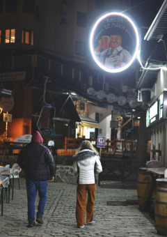 Twee mensen wandelen ‘s avonds over een kasseienstraat in een vakantiepark met glamping-accommodaties.