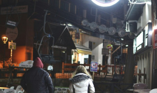 Deux personnes marchent sur une rue pavée la nuit dans un parc de vacances qui propose du glamping.