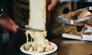 Queso fundido se raspa desde una rueda sobre patatas en el puesto de comida de un parque de vacaciones glamping.