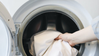 Una persona mete sábanas blancas en una lavadora en Les Chalets Huttopia de Font-Romeu, Occitania, Francia.