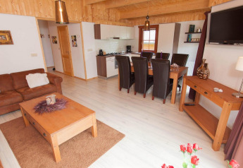 Warme lodgewoonkamer met open keuken, eet- en zithoek, houten meubels en veel natuurlijk licht.