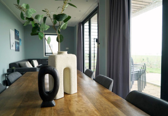 Moderne spisestue med træbord, unikke vaser og udsigt til terrasse i Mode 6-lodgen i De Achterhoek.