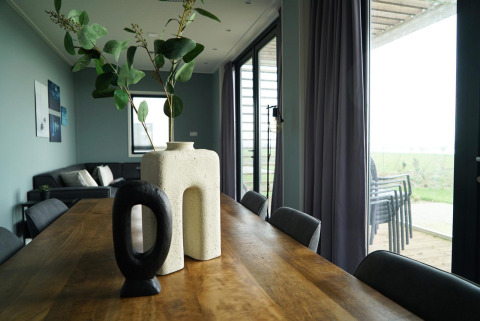 Comedor moderno con mesa de madera, jarrones únicos y vista a la terraza en Mode 6 lodge en De Achterhoek.